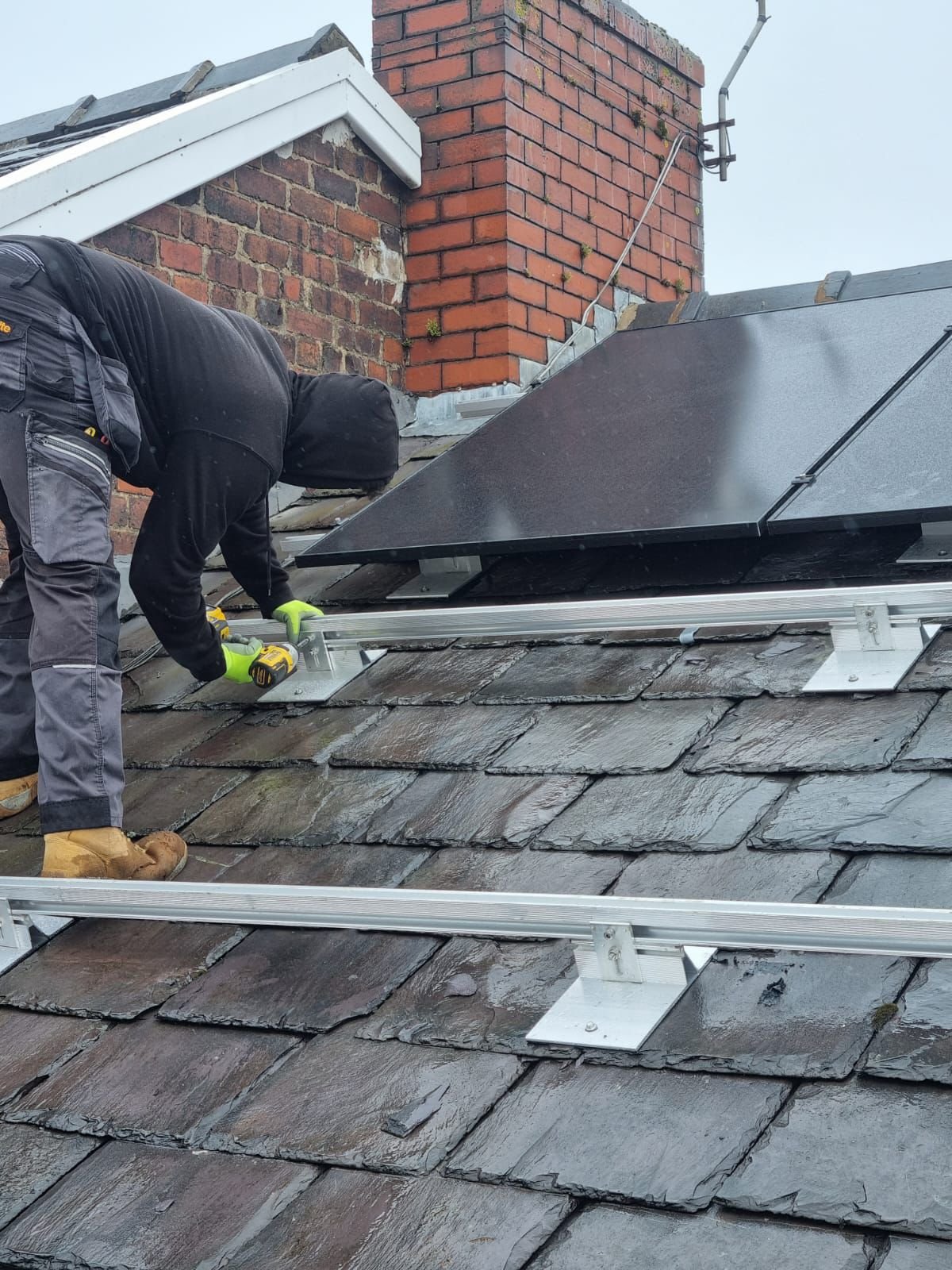 MCS-certified solar installer fitting panel mounting rails to a slate roof